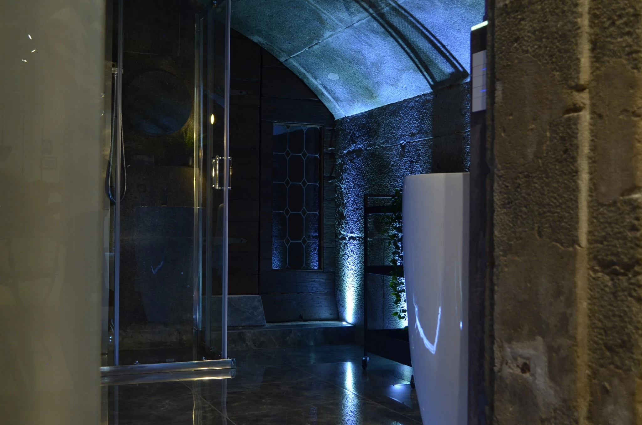 Blue ambient light revealing a restored arched stone shower space